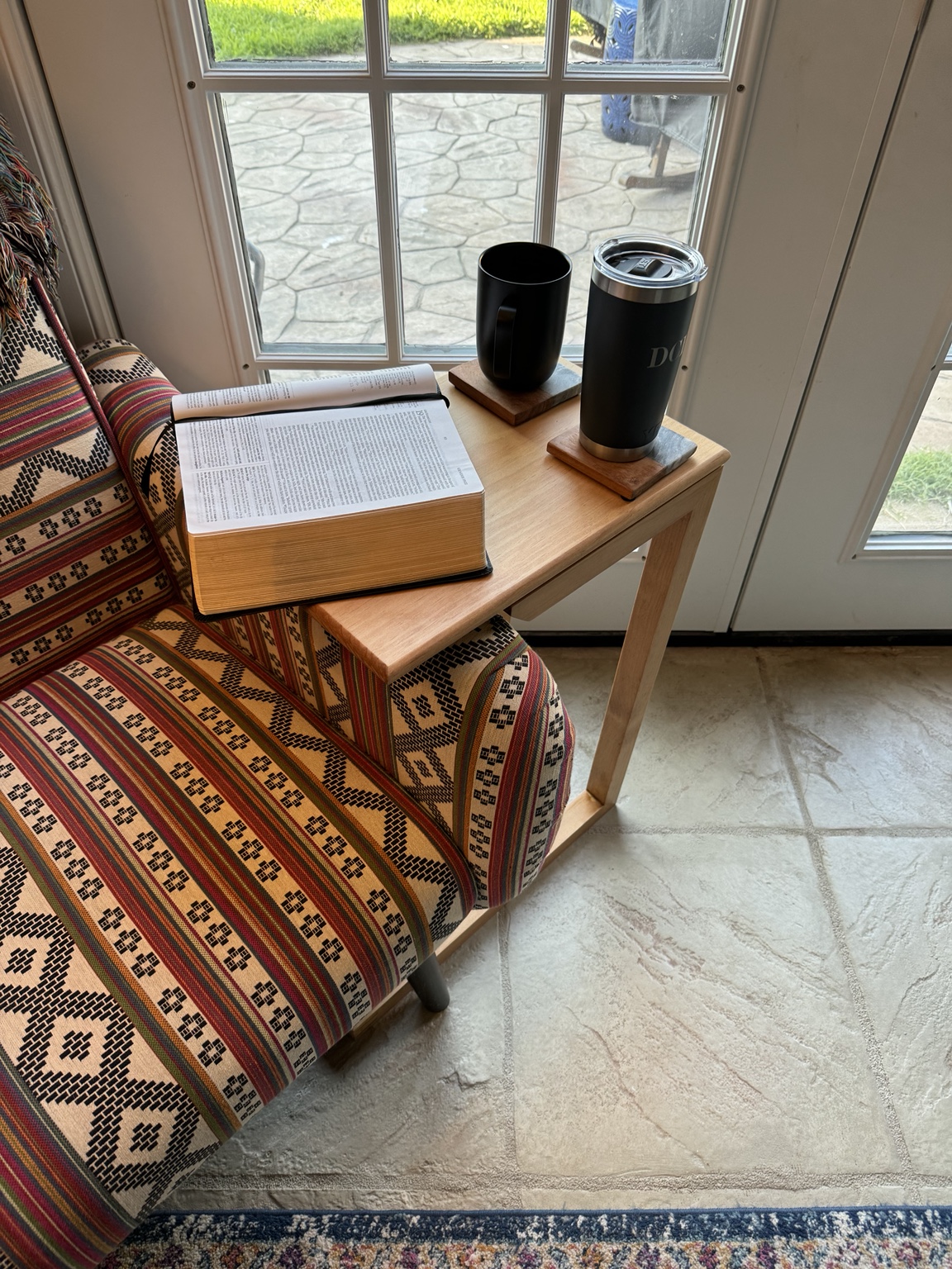 An open Bible and two drinks on Steve’s handmade pine C-table beside his favorite chair