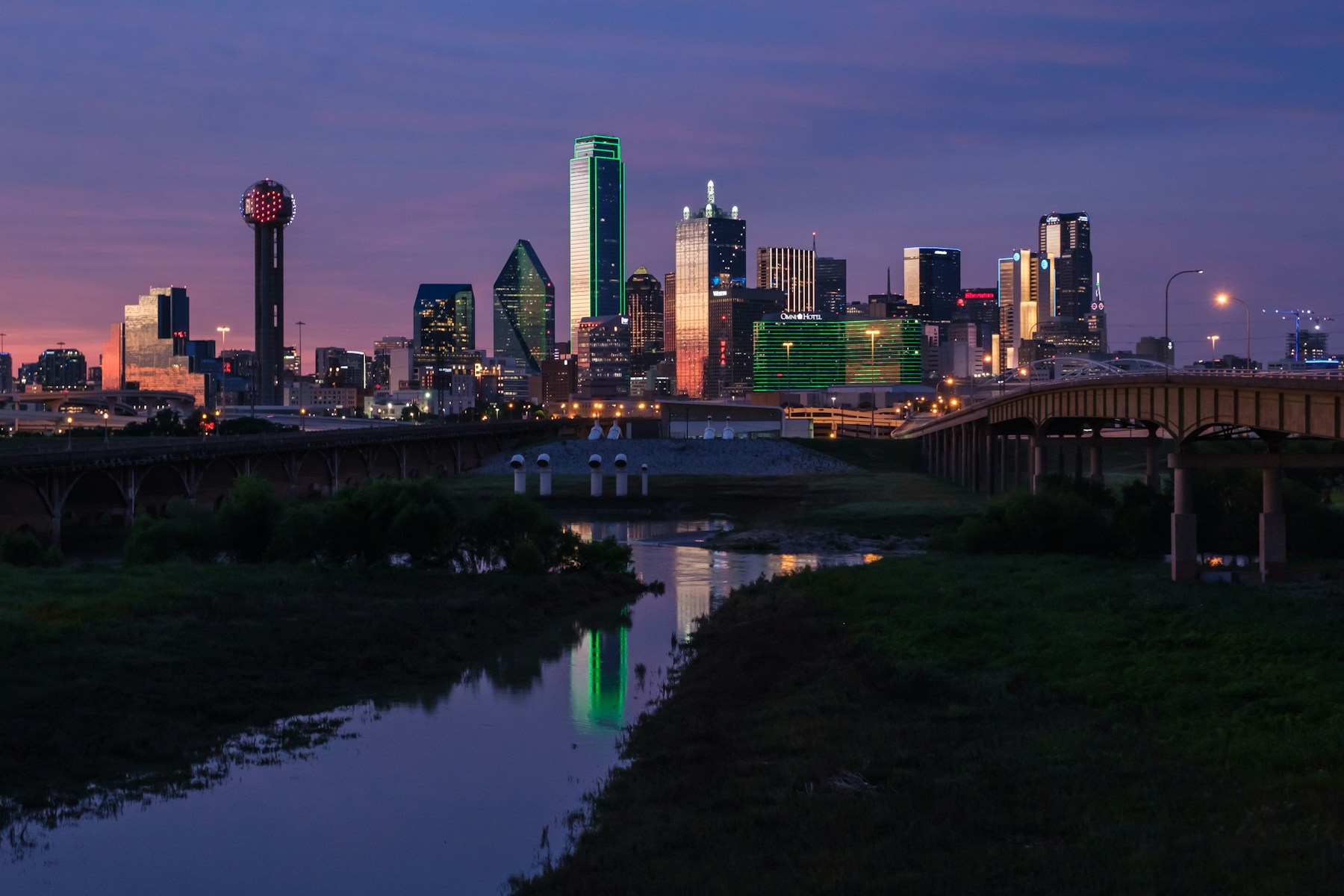 Dallas skyline at dusk, with Reunion Tower and illuminated buildings reflected in the Trinity River