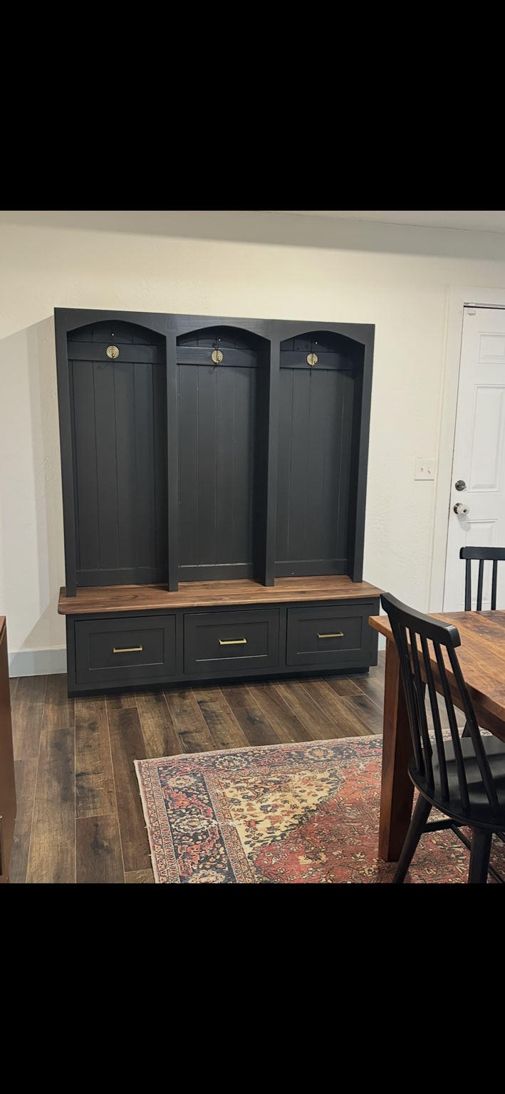 Dark painted hall tree with three coat-hook bays, a wooden bench seat, and three drawers