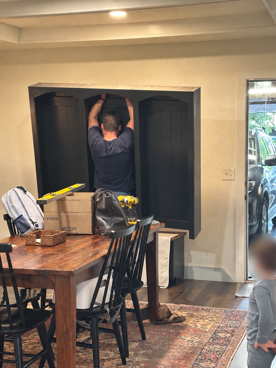 Steve installing the hall tree at home; the child’s face is blurred