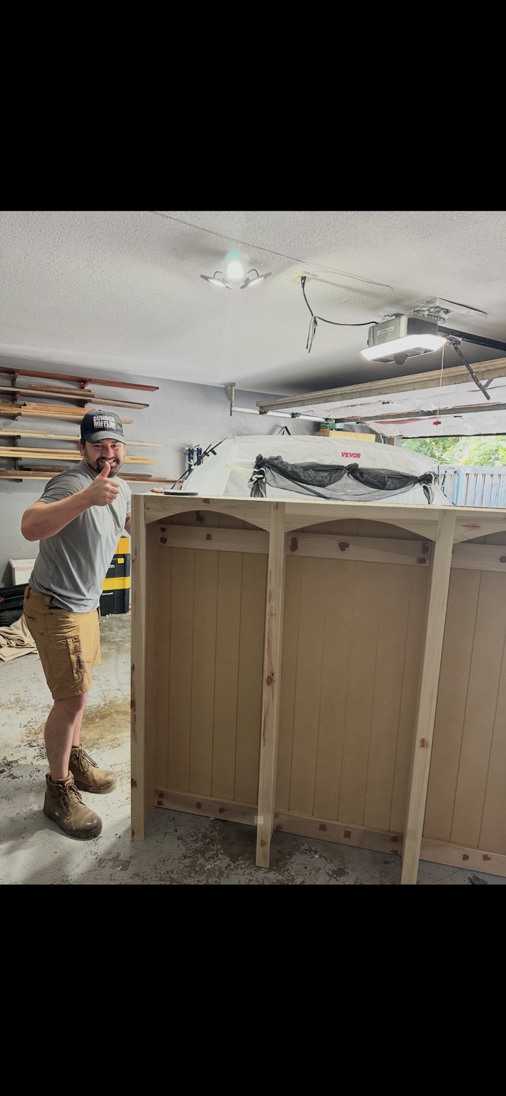 Steve in his garage workshop beside the unfinished hall tree, giving a thumbs-up