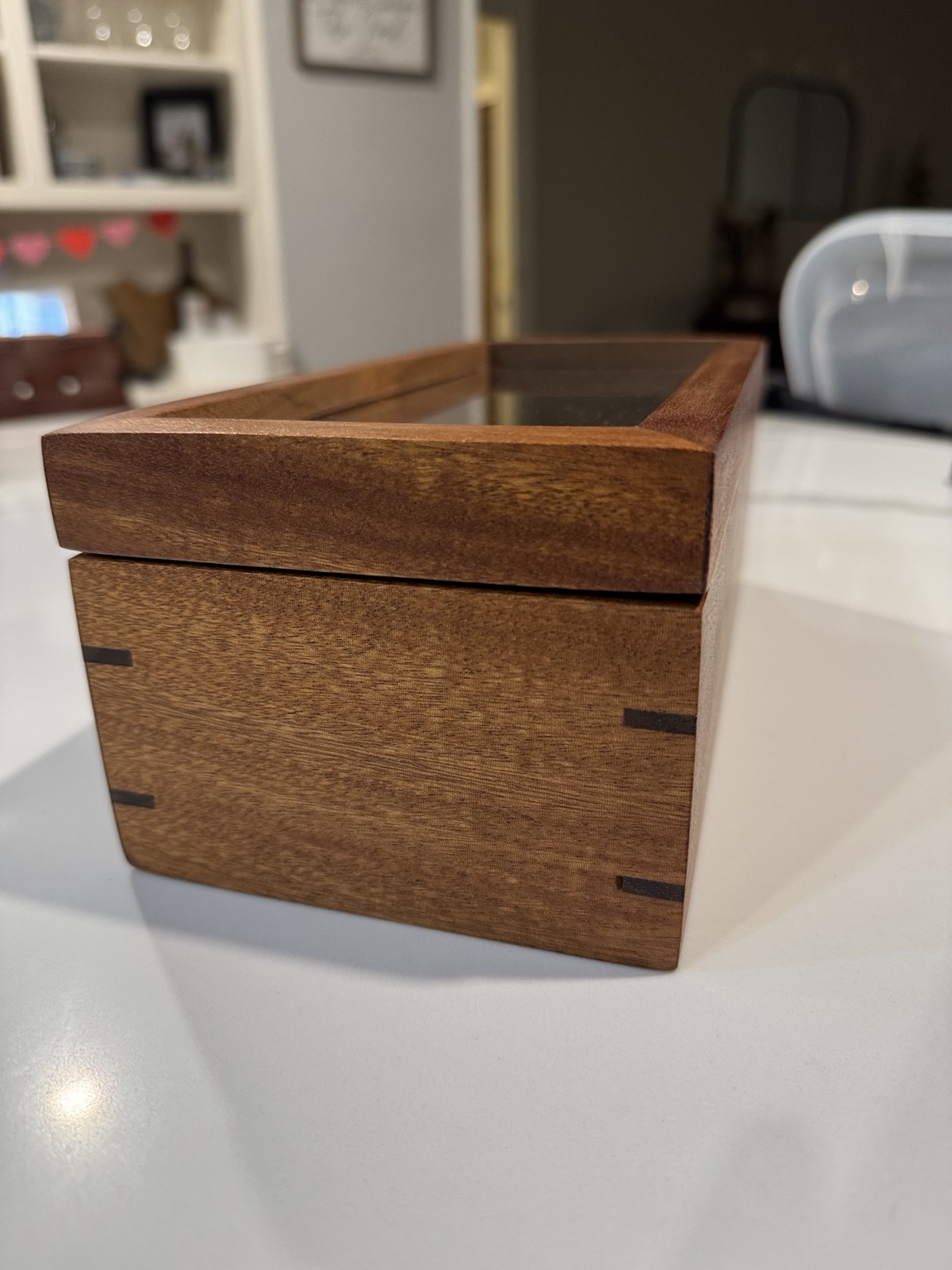 Close view of the wooden box corner, showing contrasting splines and the closed lid